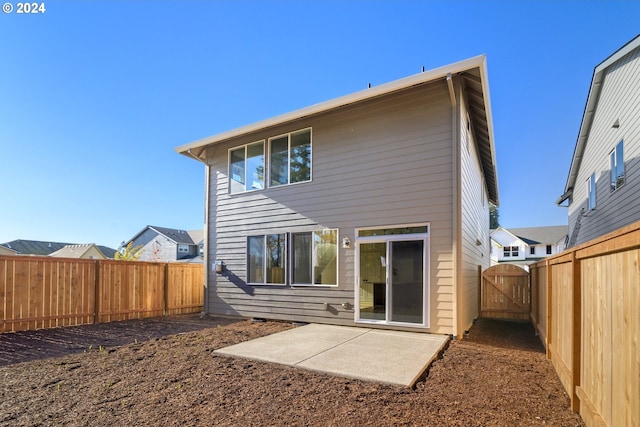 rear view of house with a gate, a fenced backyard, and a patio