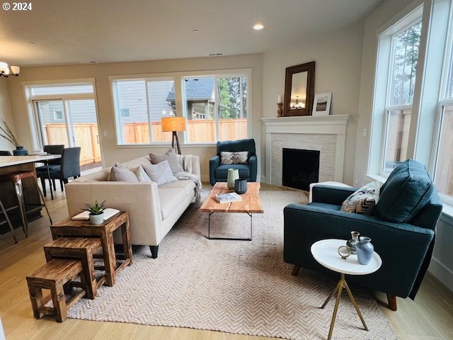 living room with a chandelier, light wood finished floors, a fireplace, and recessed lighting