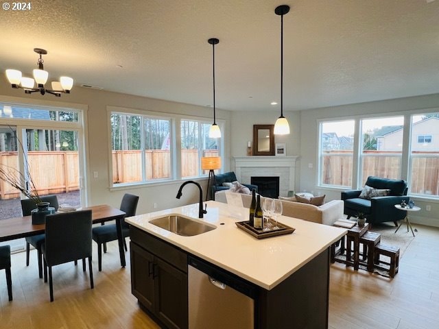 kitchen with a kitchen island with sink, light countertops, dishwasher, and a sink