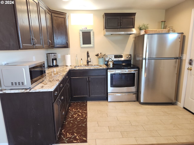 29840 Mary St, Gold Beach, OR 97444 - kitchen with a sink, light stone counters, under cabinet range hood, appliances with stainless steel finishes, and dark brown cabinets