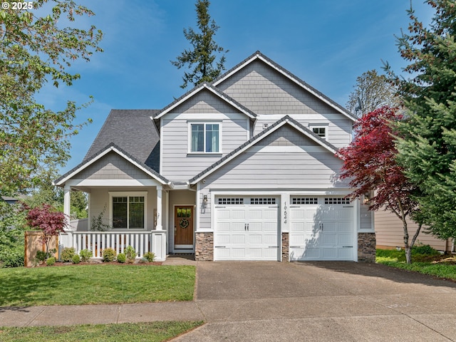 craftsman house featuring a porch, concrete driveway, stone siding, and a front lawn