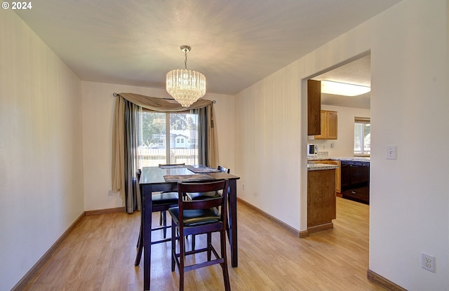 dining space with light hardwood / wood-style floors and a chandelier