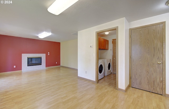 laundry area featuring cabinets, light wood-type flooring, a textured ceiling, a fireplace, and independent washer and dryer