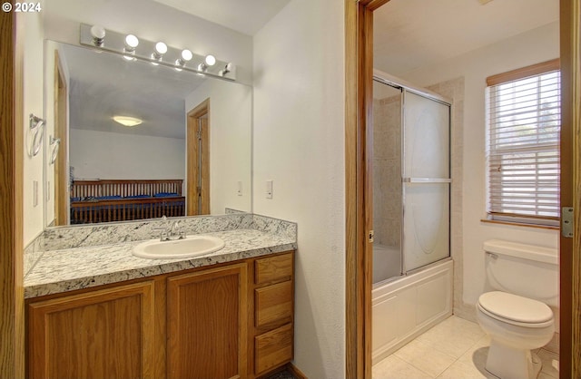 full bathroom with combined bath / shower with glass door, vanity, tile patterned flooring, and toilet