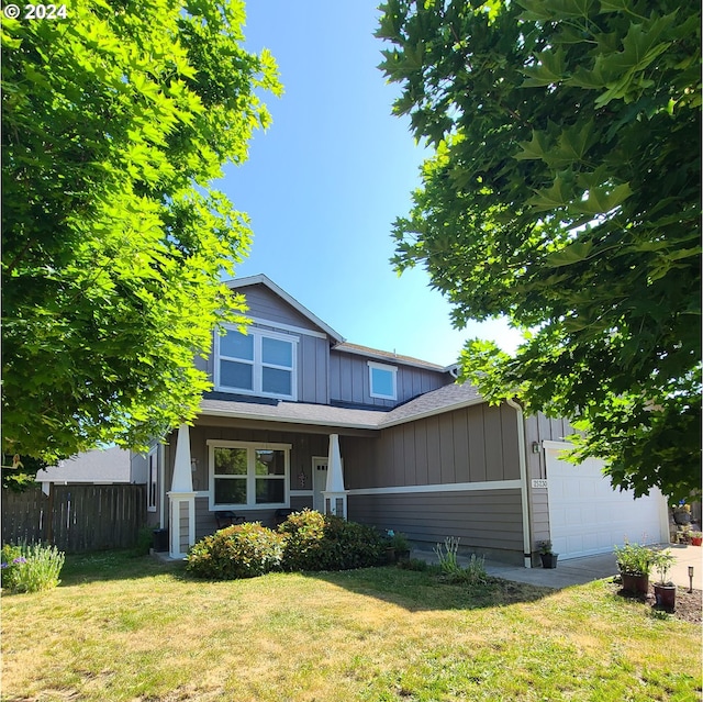 view of front of property featuring a porch, a garage, and a front yard