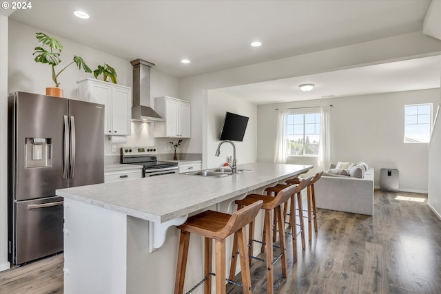 kitchen featuring white cabinets, stainless steel appliances, an island with sink, wall chimney exhaust hood, and sink