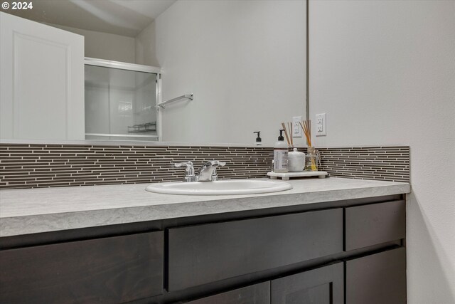 bathroom featuring backsplash, an enclosed shower, and vanity