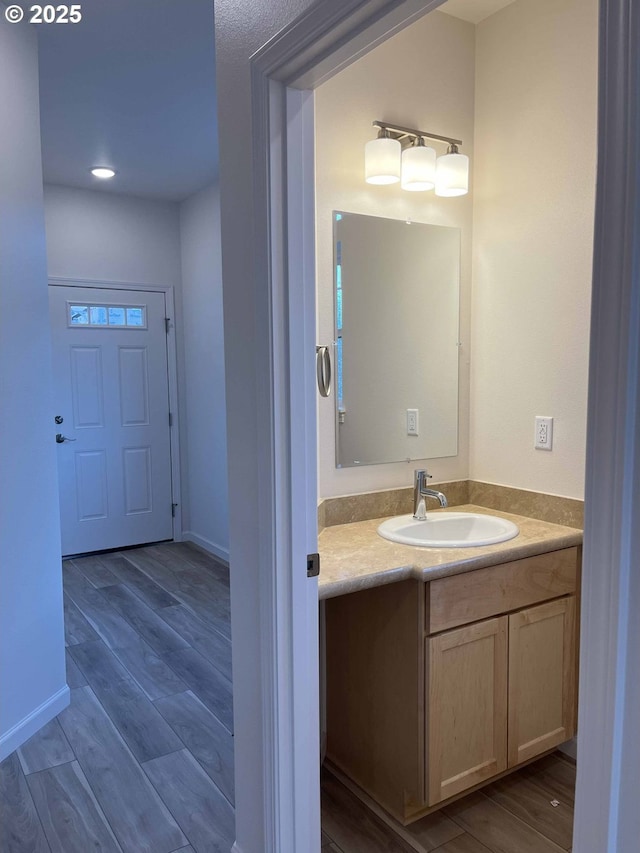 bathroom with wood finished floors, vanity, and baseboards