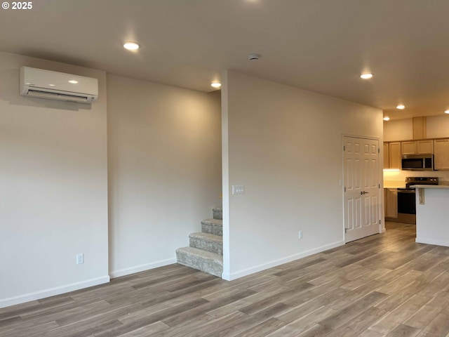 interior space with recessed lighting, light wood-style flooring, baseboards, and a wall mounted air conditioner