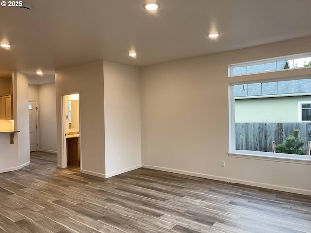 unfurnished room with baseboards, wood finished floors, and recessed lighting