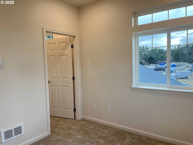 carpeted empty room with visible vents and baseboards