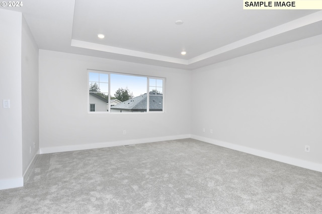 empty room with recessed lighting, a raised ceiling, baseboards, and carpet floors