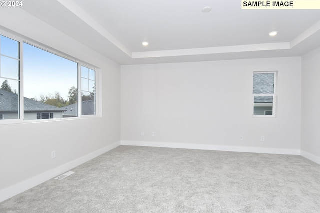 carpeted empty room with recessed lighting, visible vents, a raised ceiling, and baseboards