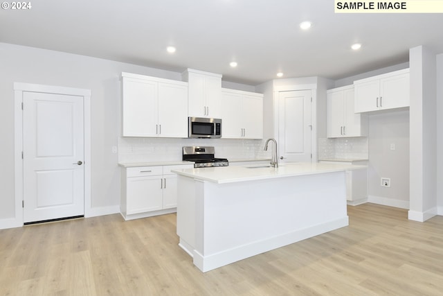 kitchen featuring stainless steel appliances, light hardwood / wood-style flooring, a kitchen island with sink, and white cabinetry