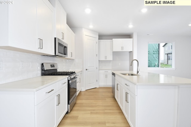 kitchen featuring tasteful backsplash, light countertops, light wood-style floors, stainless steel appliances, and a sink