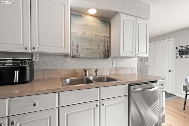 kitchen featuring white cabinets, light hardwood / wood-style flooring, sink, and dishwasher