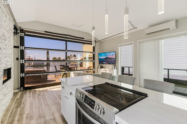 kitchen featuring a wall mounted air conditioner, light wood-type flooring, decorative light fixtures, white cabinetry, and stainless steel electric range