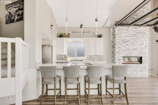 kitchen featuring stainless steel fridge, sink, pendant lighting, white cabinets, and light hardwood / wood-style floors