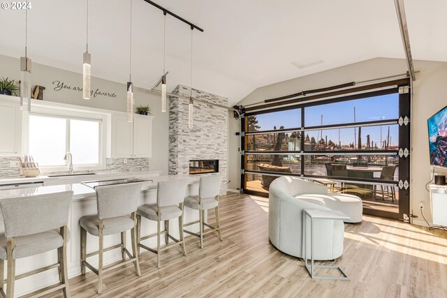 living room featuring vaulted ceiling, sink, a fireplace, and light hardwood / wood-style flooring