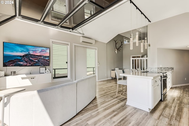 kitchen featuring pendant lighting, white cabinets, an AC wall unit, electric stove, and light wood-type flooring