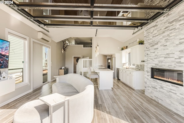 living room featuring high vaulted ceiling, sink, a wall mounted AC, light hardwood / wood-style floors, and a tiled fireplace