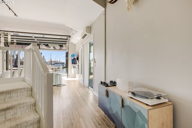 corridor with an AC wall unit, track lighting, and light wood-type flooring