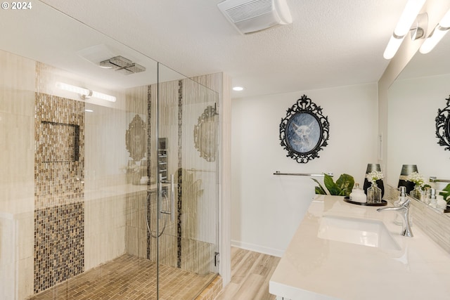 bathroom with vanity, hardwood / wood-style floors, a textured ceiling, and a shower with door