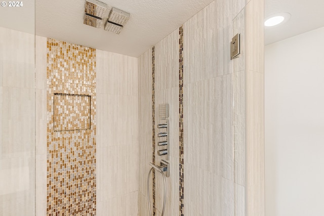 bathroom with tiled shower and a textured ceiling