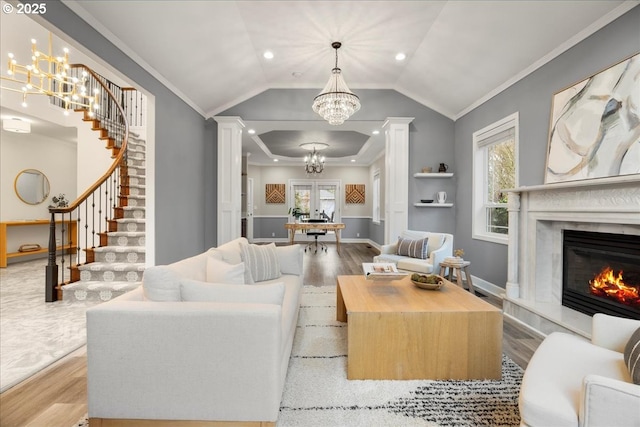 living room with lofted ceiling, a fireplace, light wood-type flooring, and ornamental molding