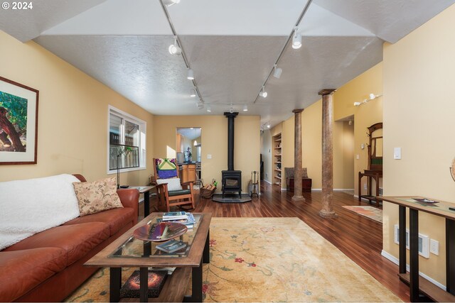 living room with track lighting, sink, built in features, dark hardwood / wood-style floors, and a wood stove