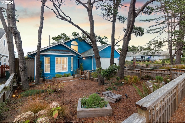 view of front of property with a garage, a vegetable garden, and fence