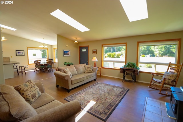 living room featuring vaulted ceiling with skylight and an inviting chandelier