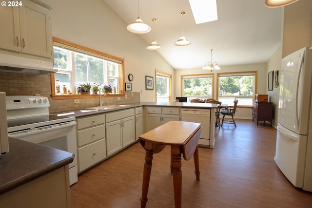 kitchen with lofted ceiling with skylight, sink, decorative light fixtures, kitchen peninsula, and white appliances