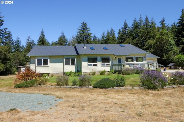 rear view of property featuring a wooden deck and a yard