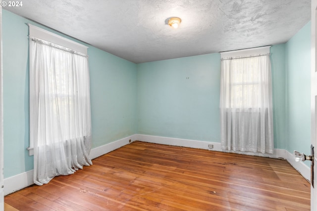 spare room featuring hardwood / wood-style floors and a textured ceiling