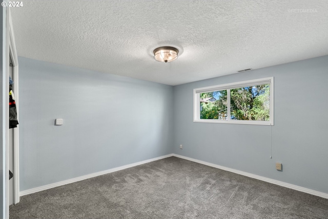 spare room with dark colored carpet and a textured ceiling