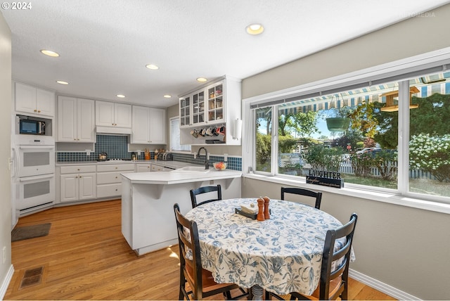 kitchen featuring kitchen peninsula, white cabinetry, plenty of natural light, and sink