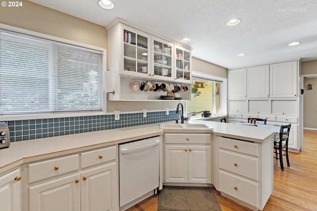 kitchen featuring dishwasher, sink, kitchen peninsula, light hardwood / wood-style floors, and white cabinetry