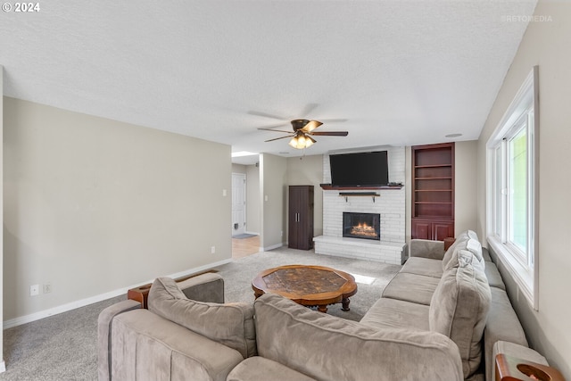 living room with ceiling fan, light colored carpet, a textured ceiling, and a brick fireplace