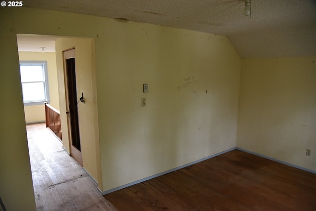 interior space featuring hardwood / wood-style floors, lofted ceiling, and a textured ceiling