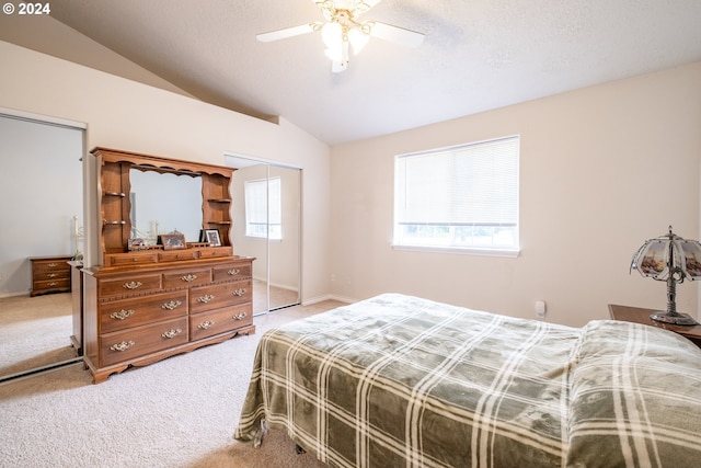 bedroom with a textured ceiling, light carpet, a ceiling fan, vaulted ceiling, and a closet