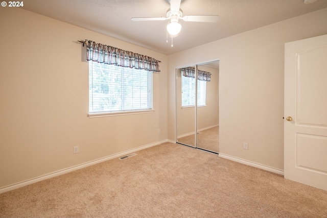 unfurnished bedroom with ceiling fan, light colored carpet, visible vents, baseboards, and a closet