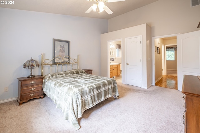 carpeted bedroom with lofted ceiling, visible vents, baseboards, a ceiling fan, and ensuite bath