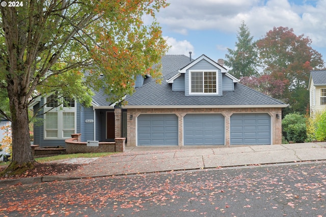 view of front of house with a garage, driveway, brick siding, and roof with shingles