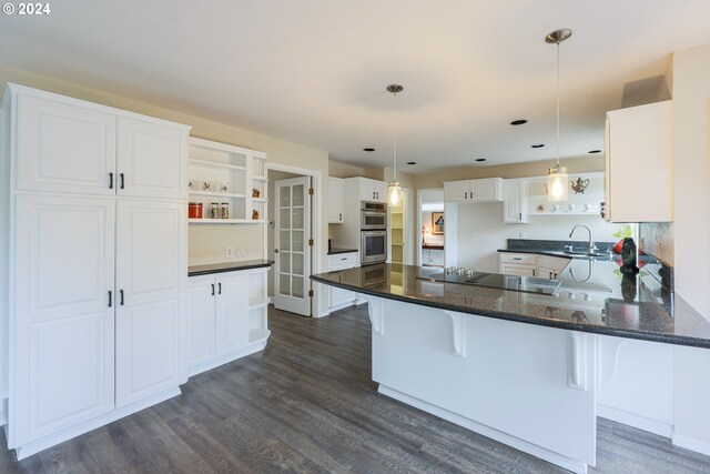 kitchen with dark hardwood / wood-style floors, black electric cooktop, a breakfast bar area, kitchen peninsula, and white cabinets