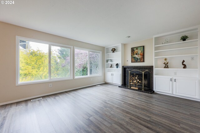 unfurnished living room with dark hardwood / wood-style flooring, built in features, and plenty of natural light