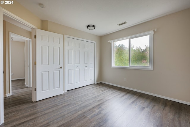 unfurnished bedroom with a closet and dark wood-type flooring