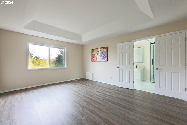 unfurnished room with a raised ceiling and dark hardwood / wood-style flooring