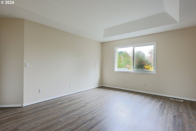 unfurnished room featuring a raised ceiling and dark hardwood / wood-style floors