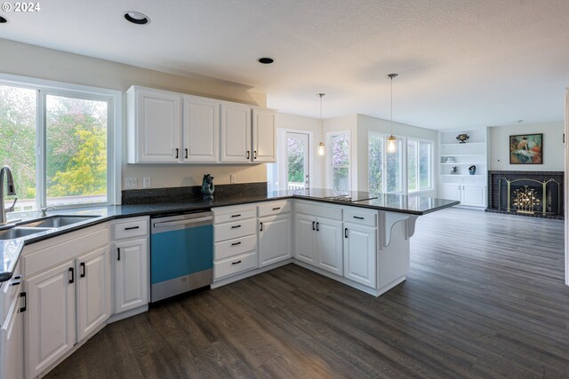 kitchen featuring kitchen peninsula, white cabinets, stainless steel dishwasher, and sink